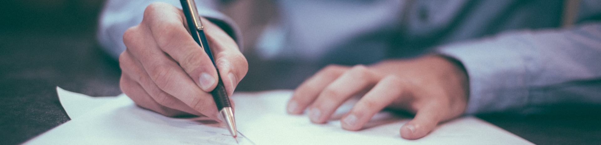 A business man using a ballpoint pent to write on paper